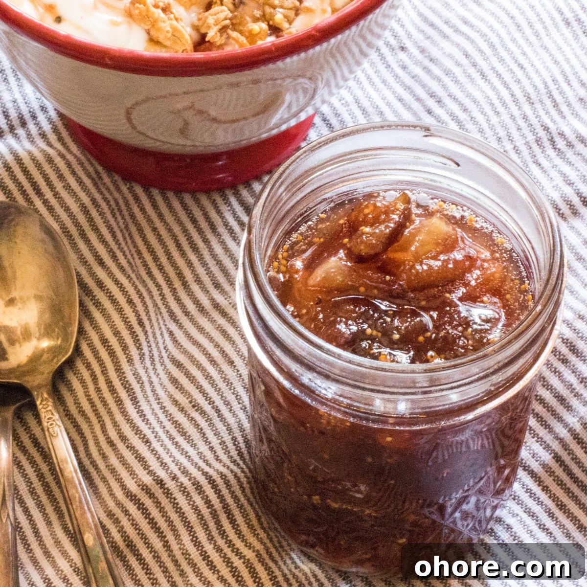Spiced Fig Jam for Canning: Homemade Preserving Recipe 2 A jar filled with fig jam, with a spoon.
