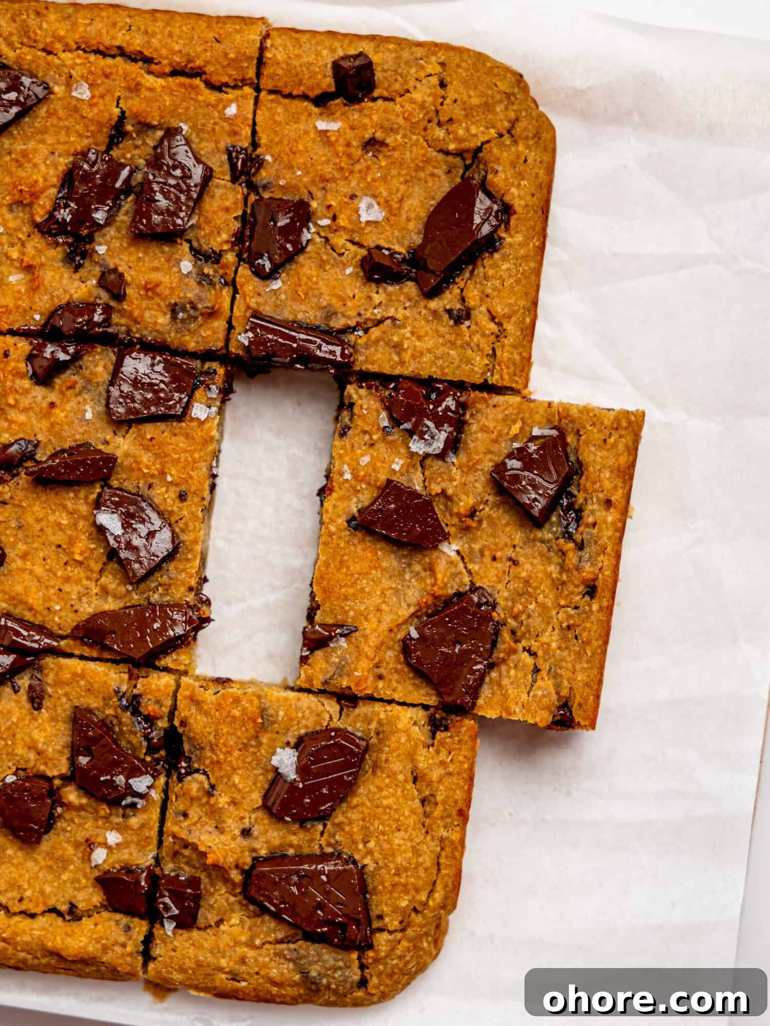 Gooey Chickpea Cookie Bars — Protein-Packed Dessert Bars 3 Bird's eye view of healthy cookie bars on a sheet of white parchment paper.