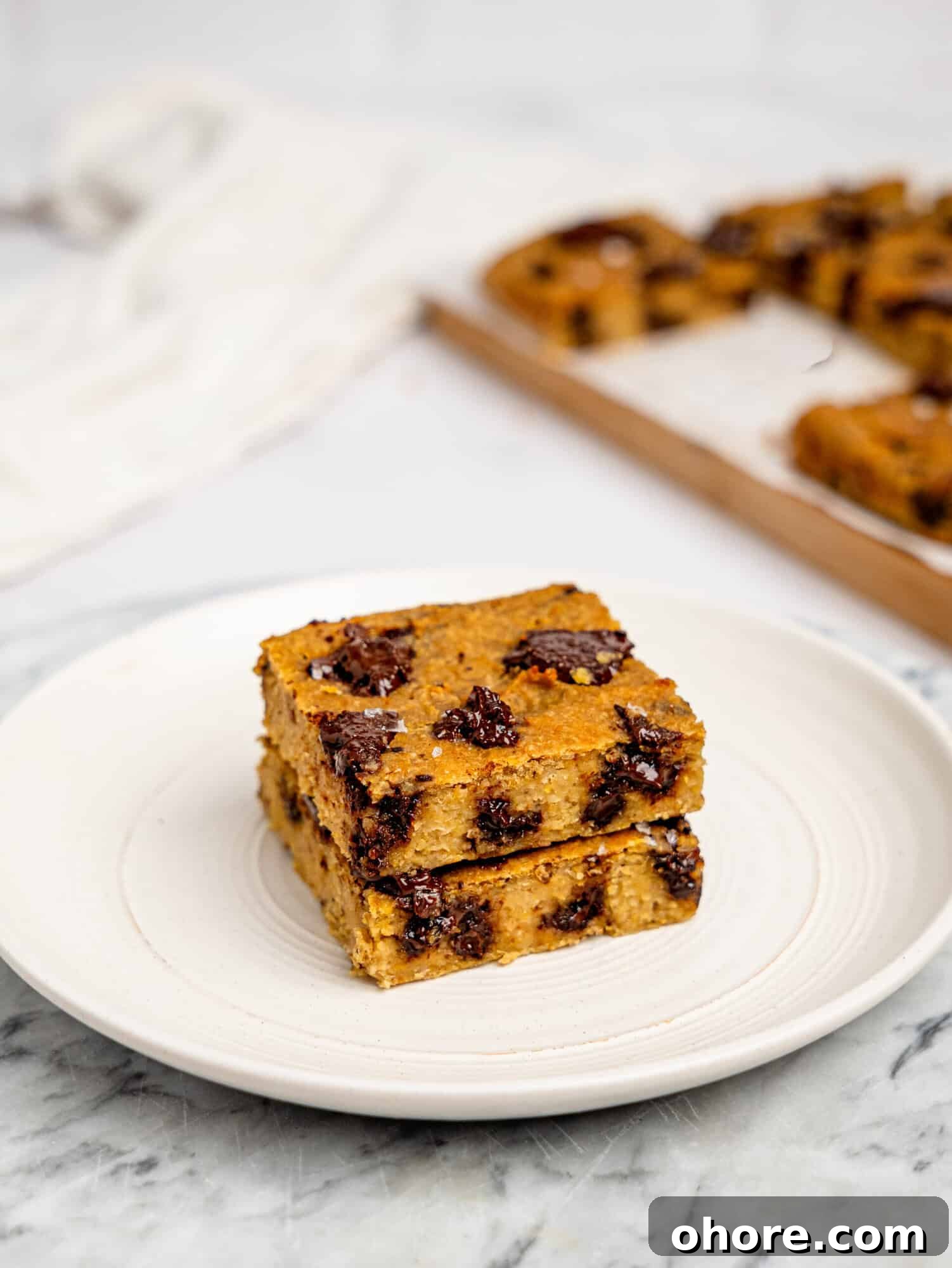 Gooey Chickpea Cookie Bars — Protein-Packed Dessert Bars 5 Two chickpea cookie bars stacked on top of each other on a white plate.