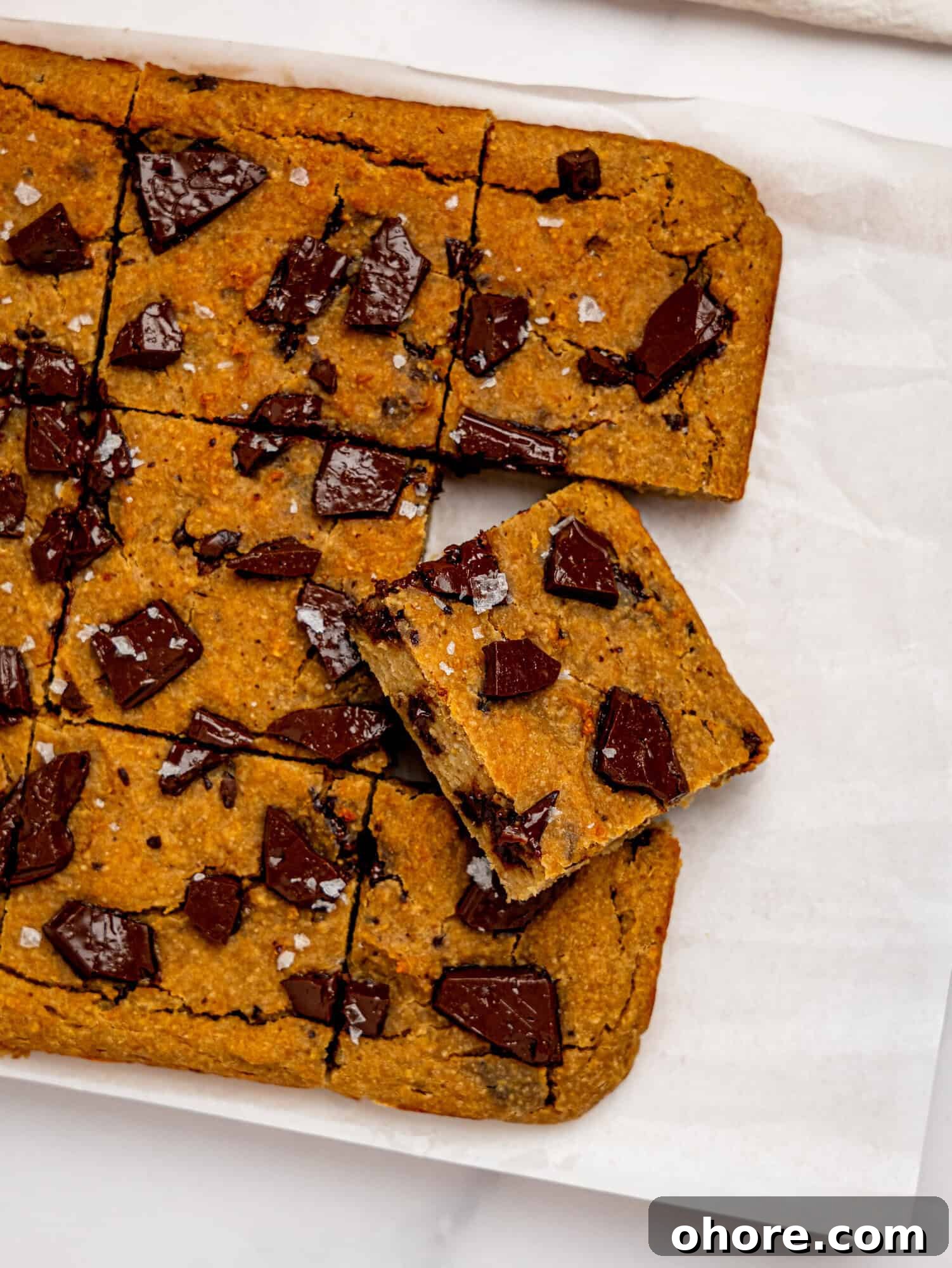 Gooey Chickpea Cookie Bars — Protein-Packed Dessert Bars 9 Bird's eye view of chickpea cookie bars on a sheet of white parchment paper.