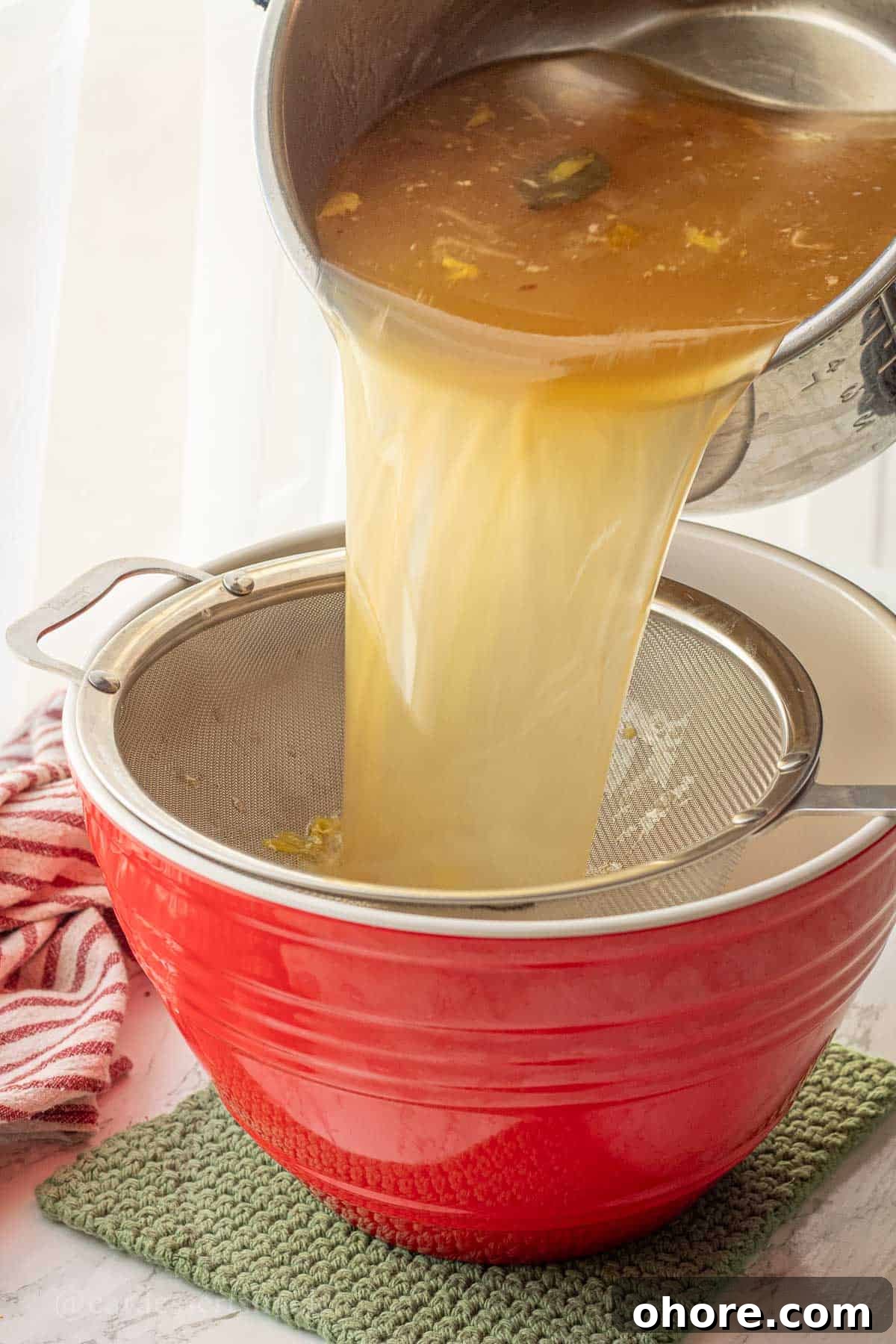 Homemade Instant Pot Chicken Bone Broth Recipe 8 Pouring chicken bone broth into mesh strainer.