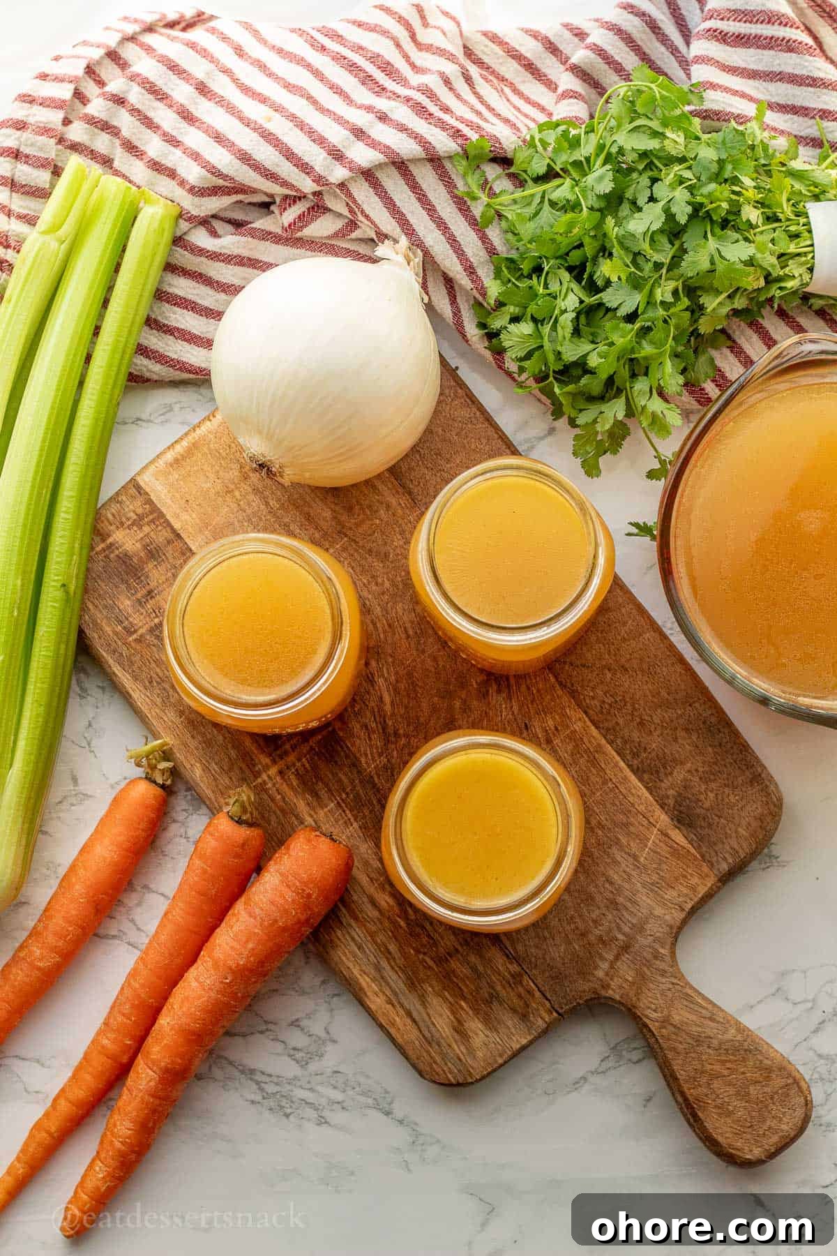 Homemade Instant Pot Chicken Bone Broth Recipe 10 Jars of chicken bone roth on wood cutting board with onion and carrots.