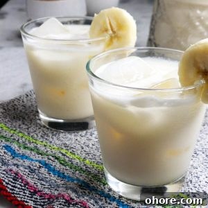 Banana Agua Fresca Recipe — Refreshing Banana Water Drink 8 Two glasses with ice and agua de platano garnished with a slice of banana
