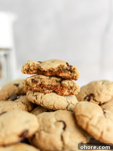 Two cookie halves on top of a pile of chocolate chip cookies.
