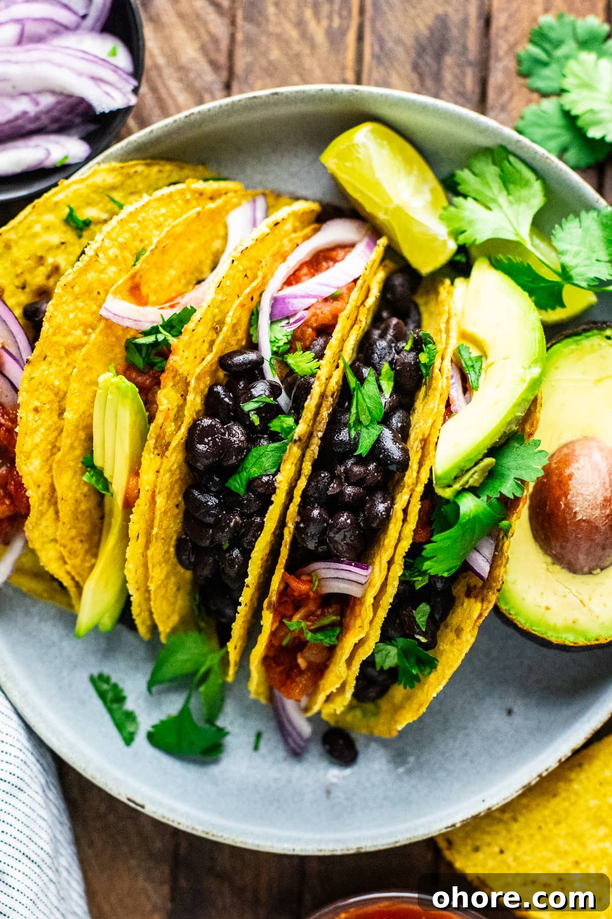 Quick Black Bean Tacos Ready in 10 Minutes 2 a group of black bean tacos on plate with condiments.