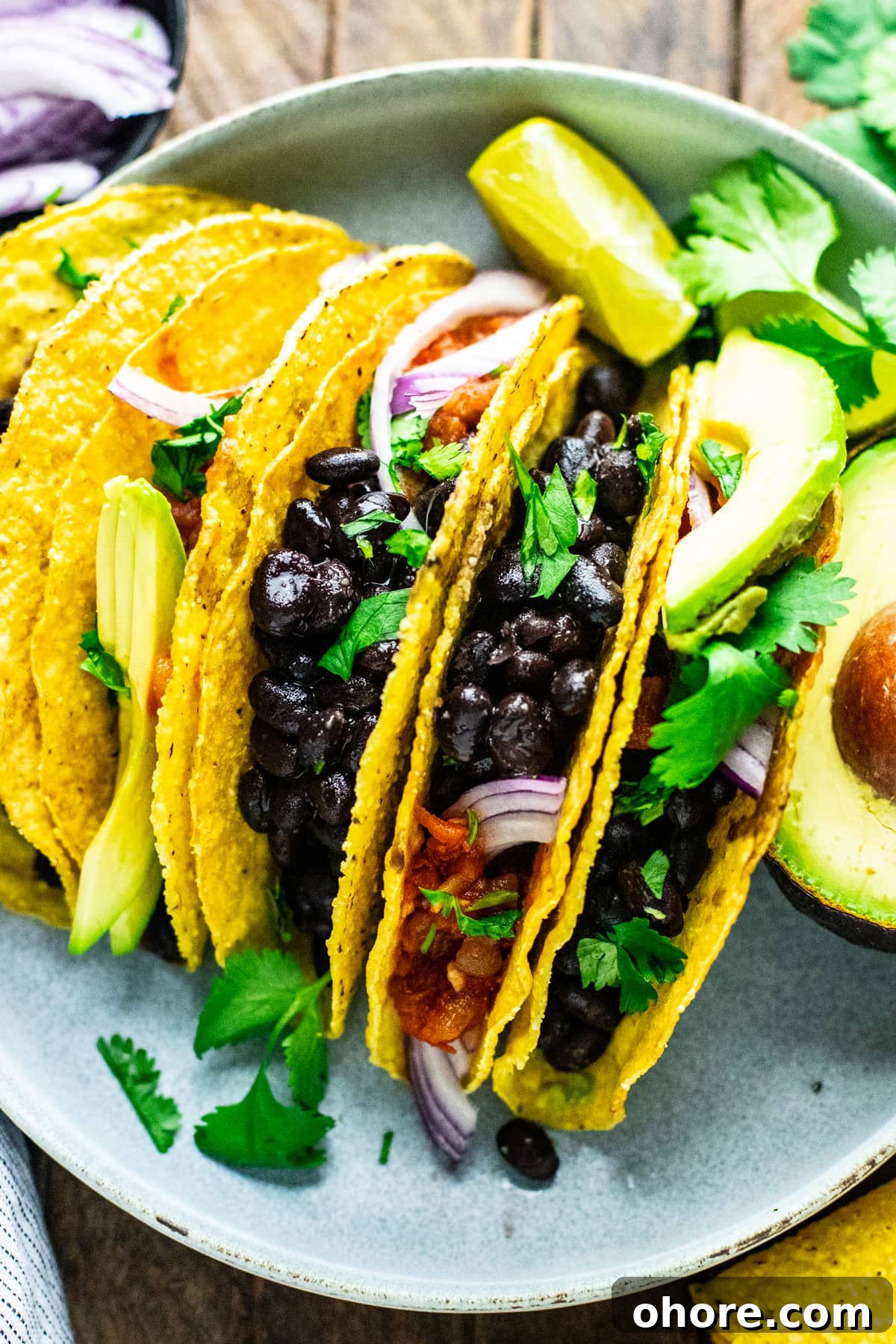 Quick Black Bean Tacos Ready in 10 Minutes 6 a group of black bean tacos on plate with condiments.