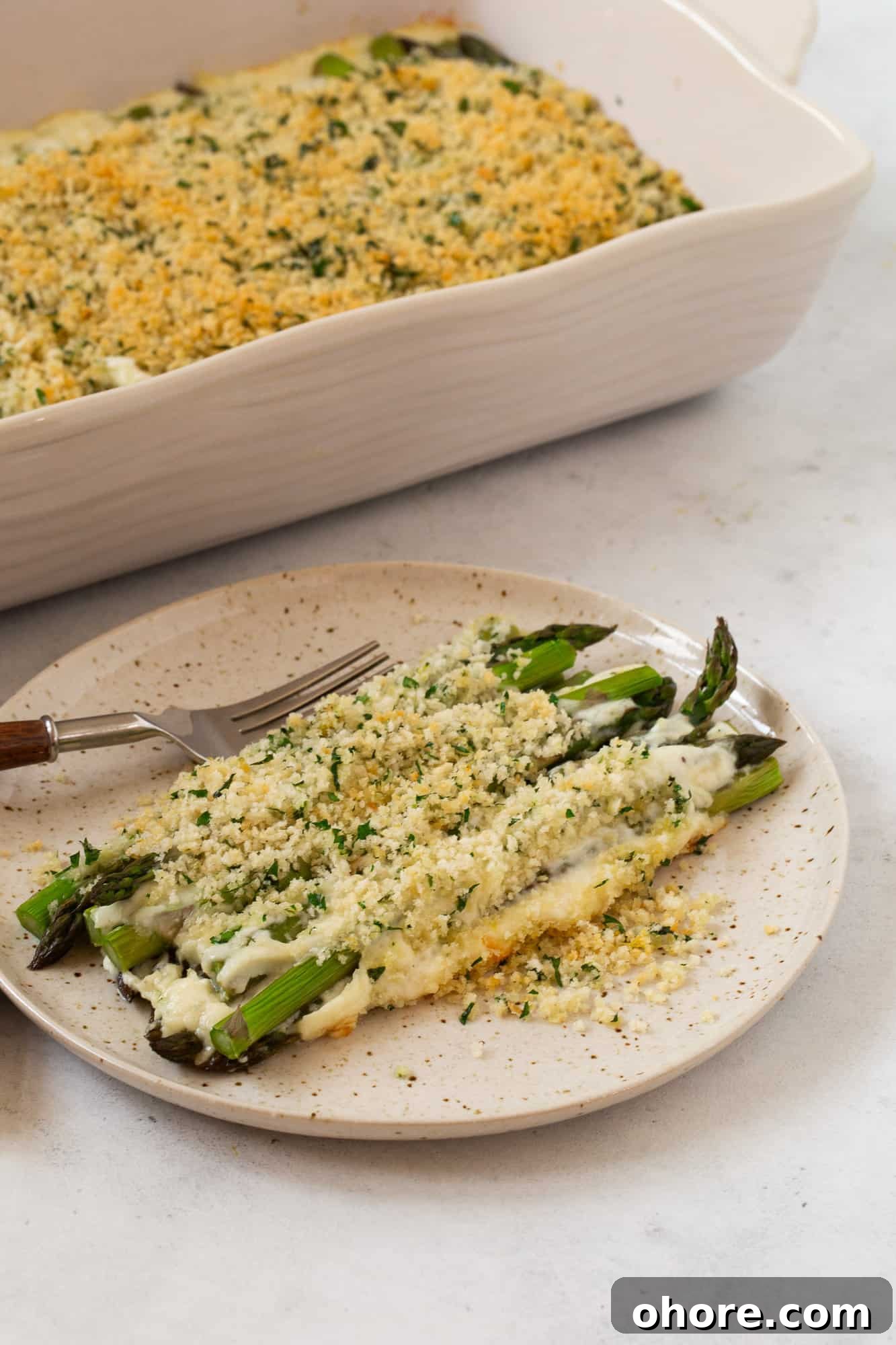 Creamy Asparagus Casserole Recipe for Spring Dinner 17 Plated asparagus casserole, with more of the casserole in the background.