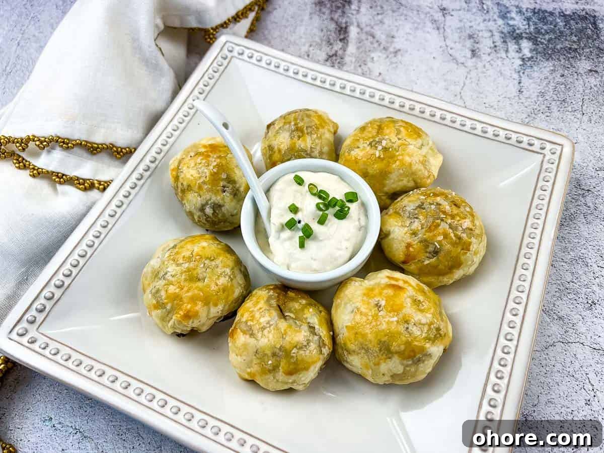Beef Wellington Bites on a white plate with sauce in the middle.