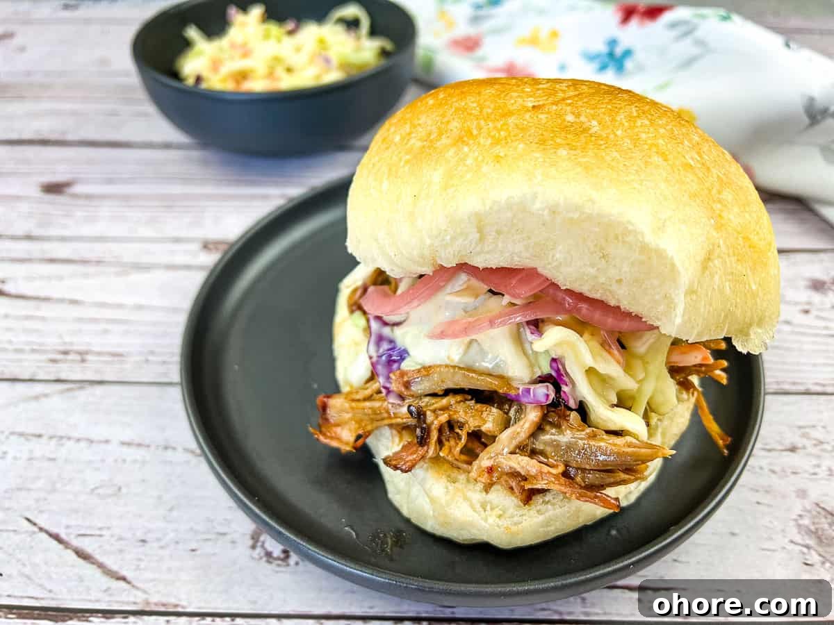 Pulled Pork Sandwich with Coleslaw on a black plate.