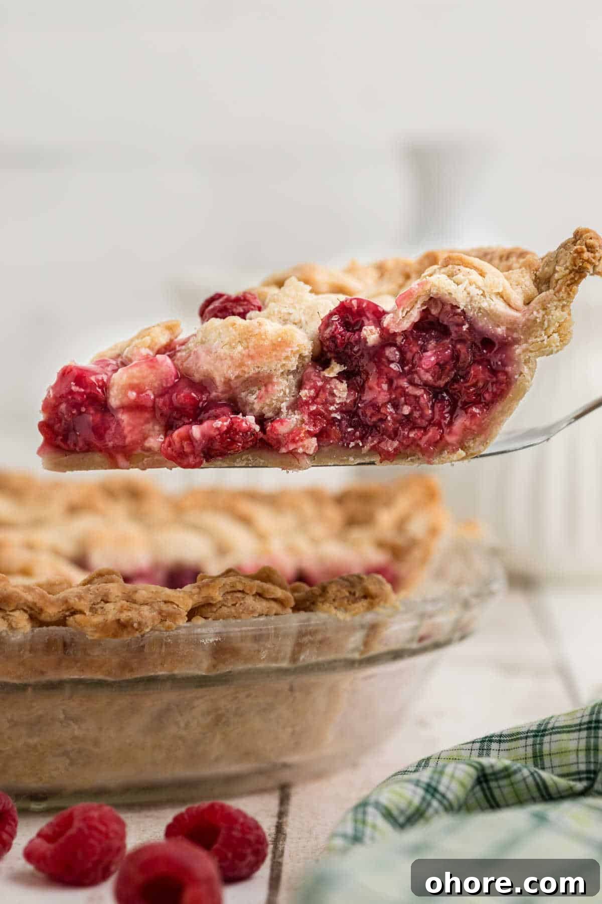 Homemade Raspberry Pie Recipe: Flaky Crust & Fresh Filling 10 A slice of raspberry pie being lifted out of a pie dish.