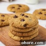 Stack of chocolate chip cookies on a cutting board.