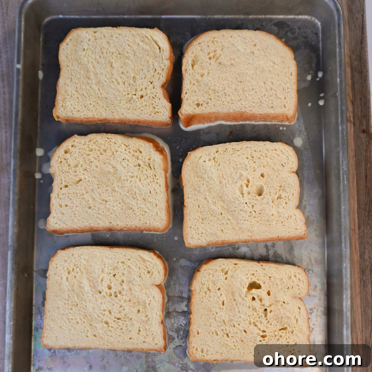 Classic French Toast Recipe: Crispy Outside, Custardy Inside 5 french toast loafs on a sheet pan.