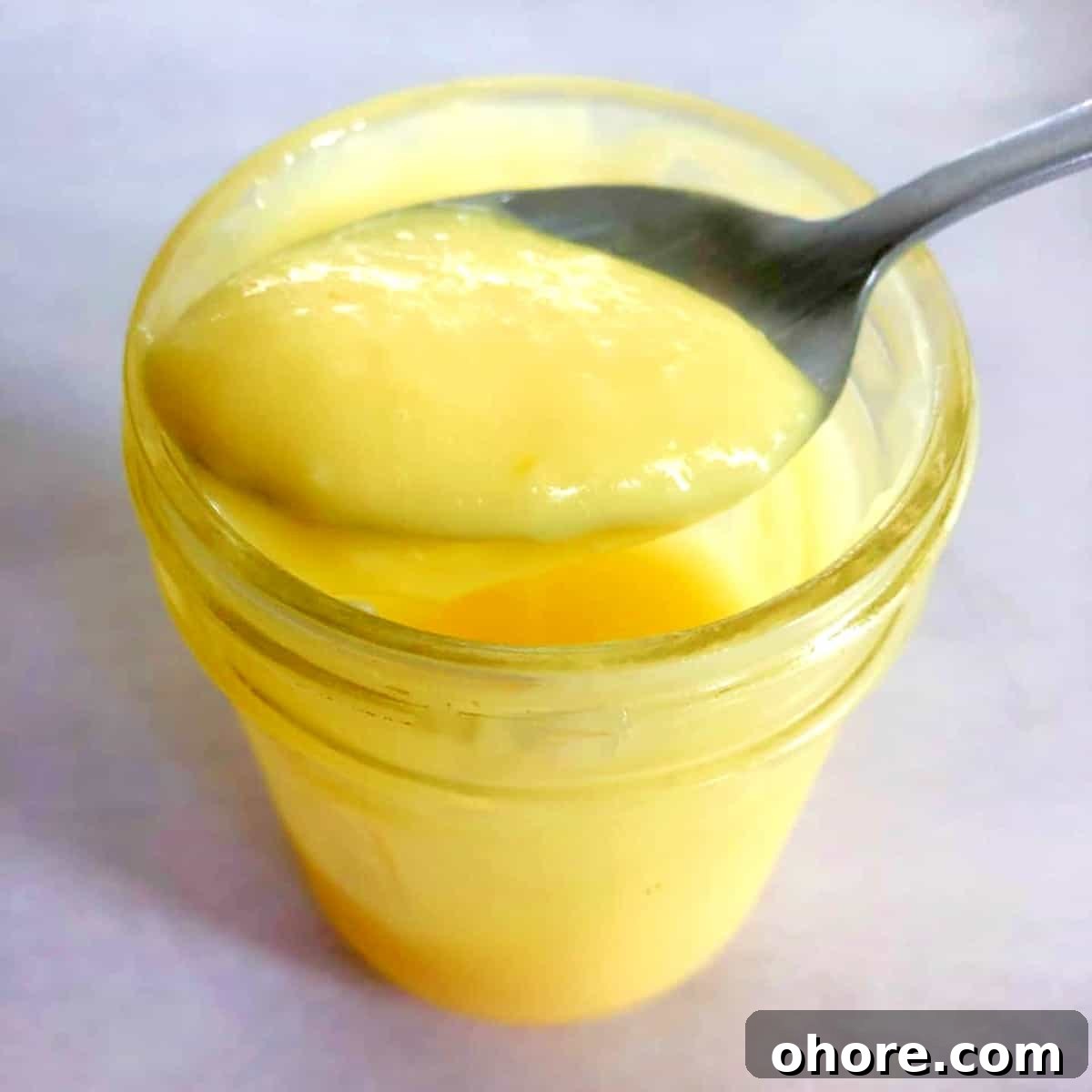 Homemade Meyer Lemon Curd Recipe — Bright Citrus Spread 2 a spoonful of lemon curd from a jar.