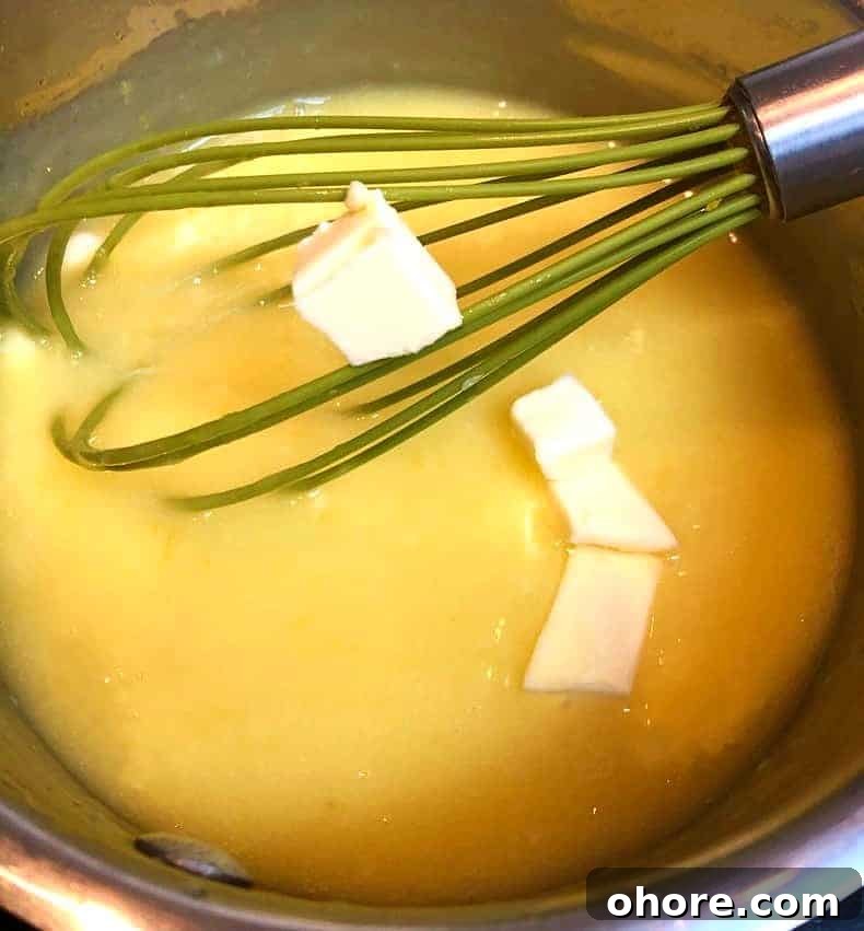 Homemade Meyer Lemon Curd Recipe — Bright Citrus Spread 4 butter added to lemon curd on stove.