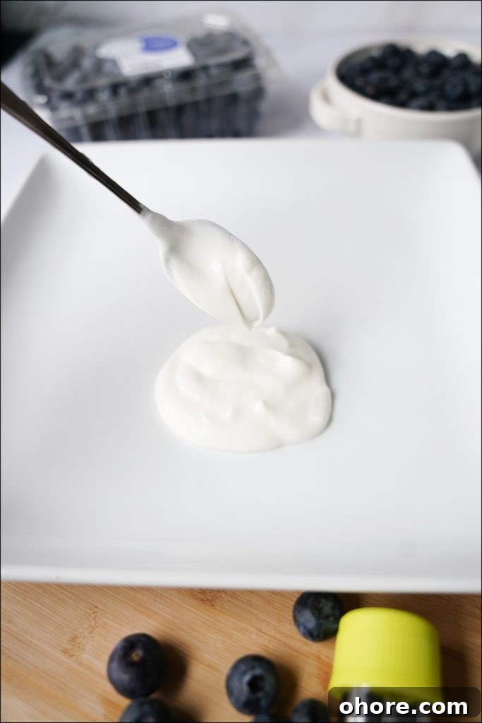 spoon with yogurt dolloping on white plate