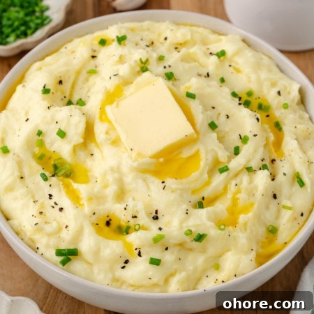 Creamy Yukon Gold Mashed Potatoes Recipe 10 Photo of a bowl full of Yukon Gold mashed potatoes with a melting slab of butter and garnished with green parsley.