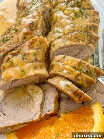 Sliced, boneless pork tenderloin with orange sauce and sliced oranges.