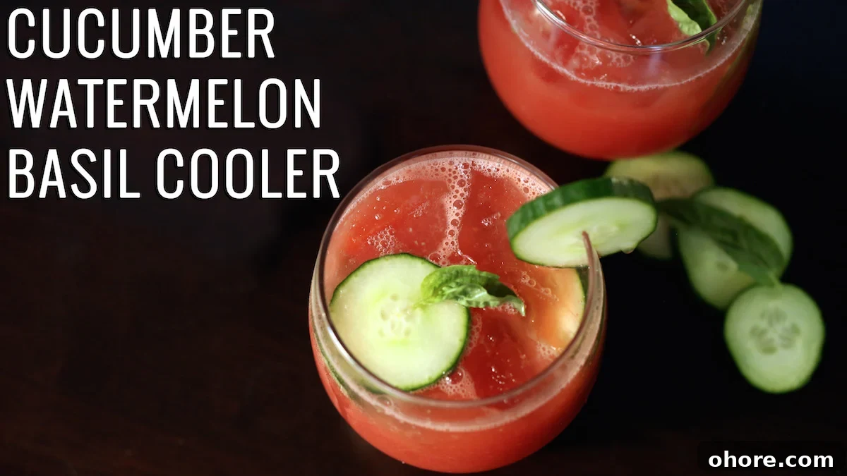 A pink-red drink in a stemless wine glass garnished with sliced cucumber and basil. Text reads "Cucumber Watermelon Basil Cooler"