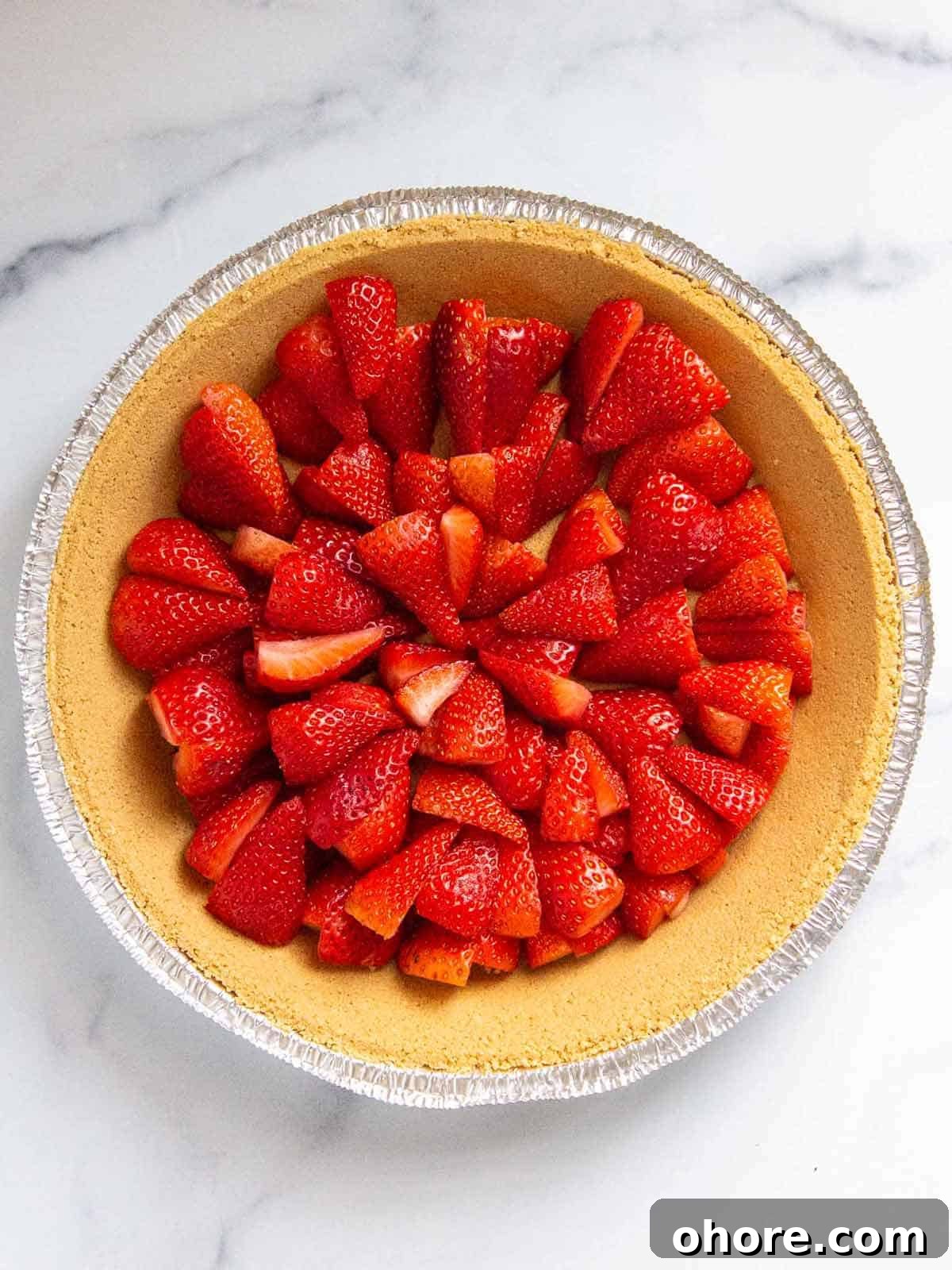 Strawberries cut side facing down in a graham cracker pie crust.