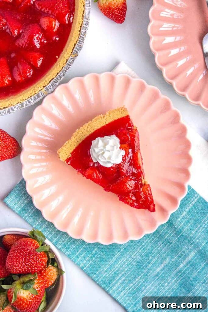 Slice of strawberry jello pie on a small plated topped with a dollop of whipped cream.