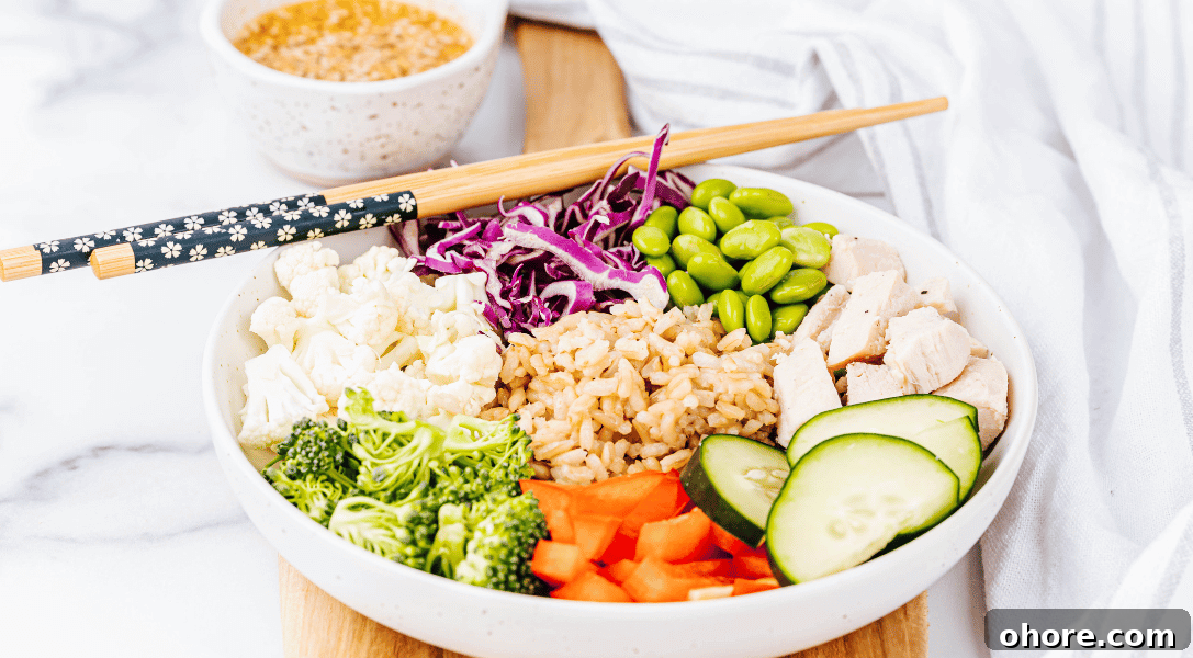 Asian Grain bowl with veggies in a white bowl with chopsticks and sauce in background