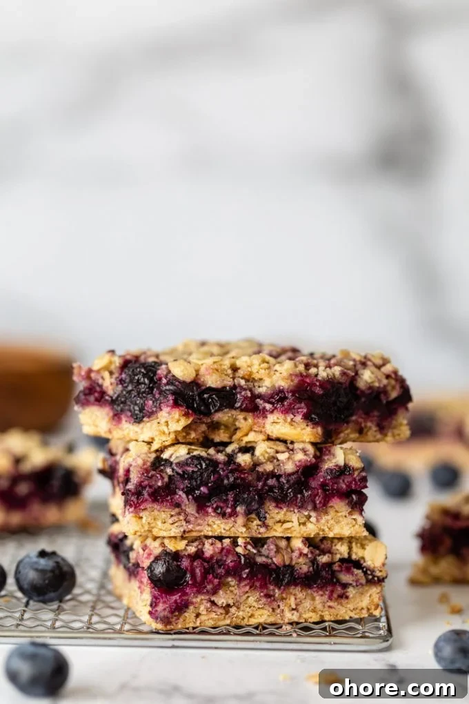 stack of blueberry crumble bars on a silver rack with blueberries around