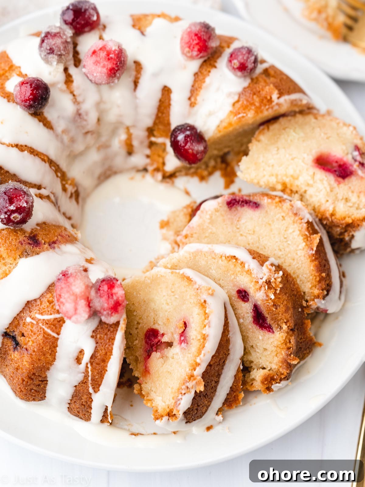 Cranberry Orange Bundt Cake with Zesty Citrus Glaze 2 Glazed cranberry orange bundt cake sliced into multiple slices on a plate.