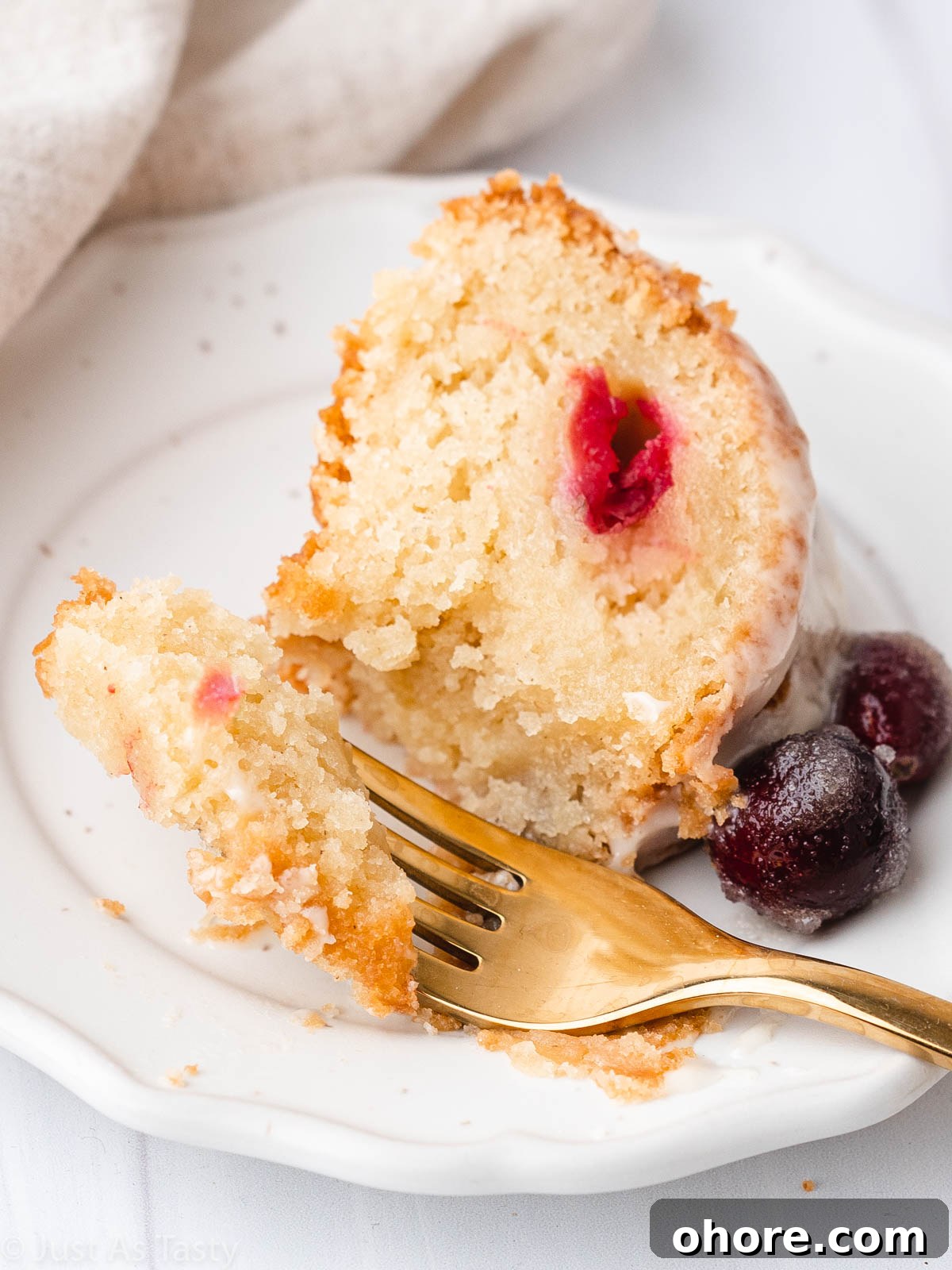 Cranberry Orange Bundt Cake with Zesty Citrus Glaze 3 A slice of cranberry orange bundt cake with orange glaze on a plate, with a bite taken on a fork.