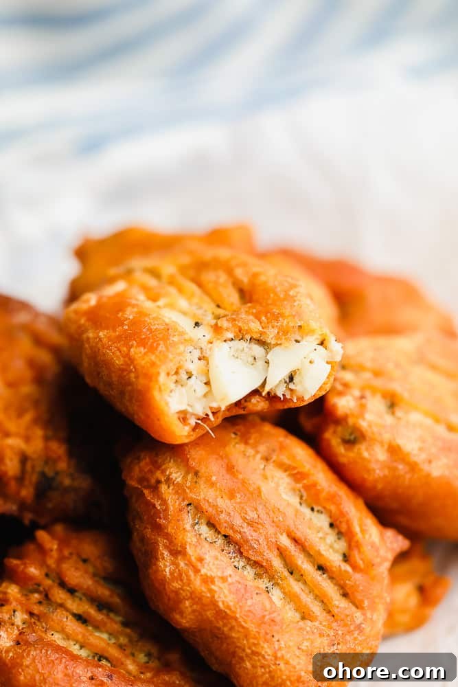 Crispy Beer-Battered Vegan Fish Fillets 2 piece of vegan fried fish with a bite missing on top of a pile of more vegan fish