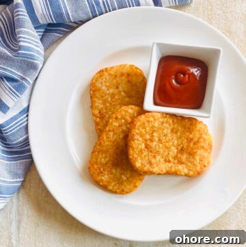 air fryer frozen hash browns on a plate with ketchup
