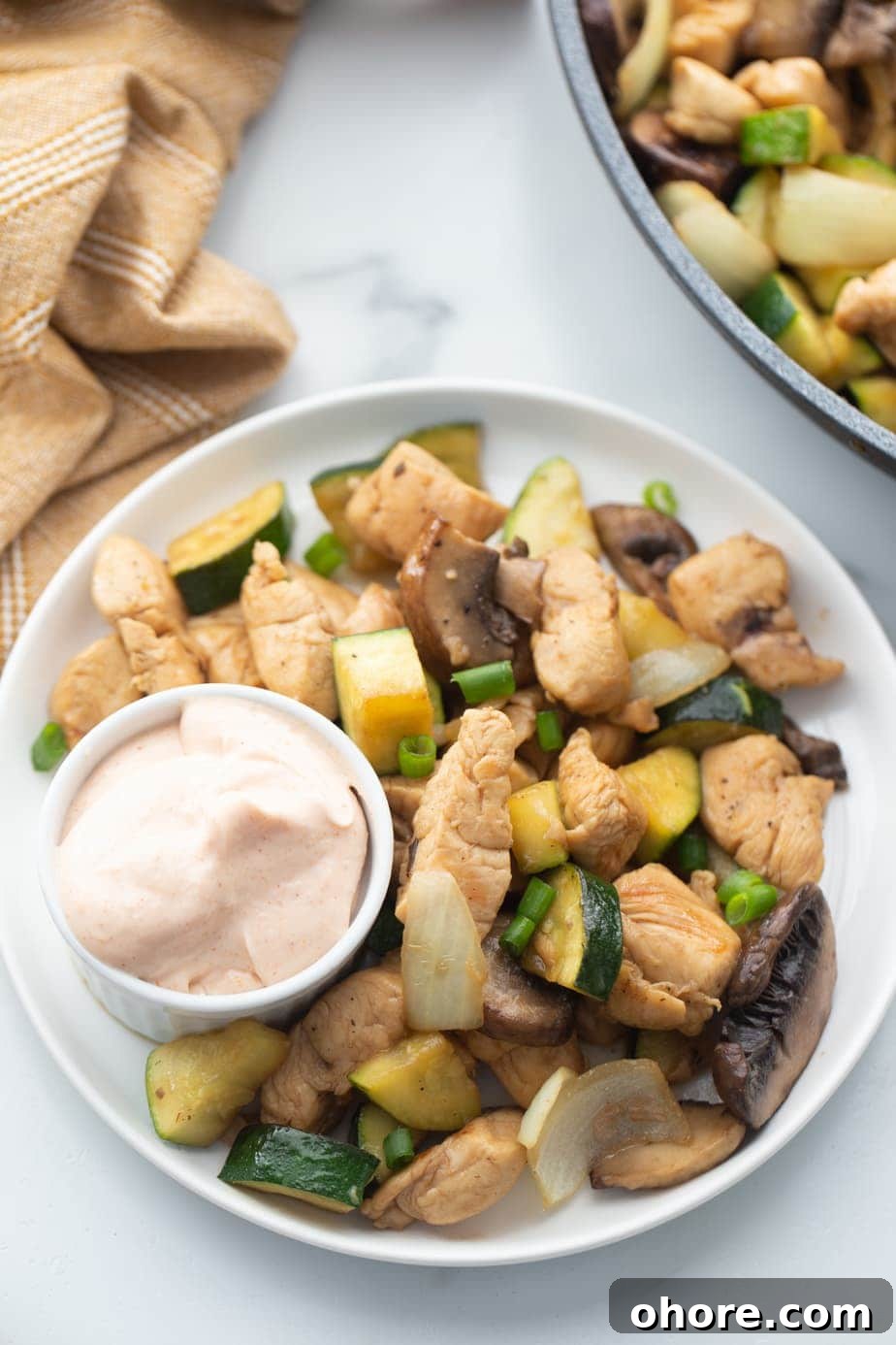 Hibachi Chicken Recipe: Tender Grilled Chicken with Garlic Butter 3 A plate is presented with chicken, veggies, and a small cup of yum you sauce.