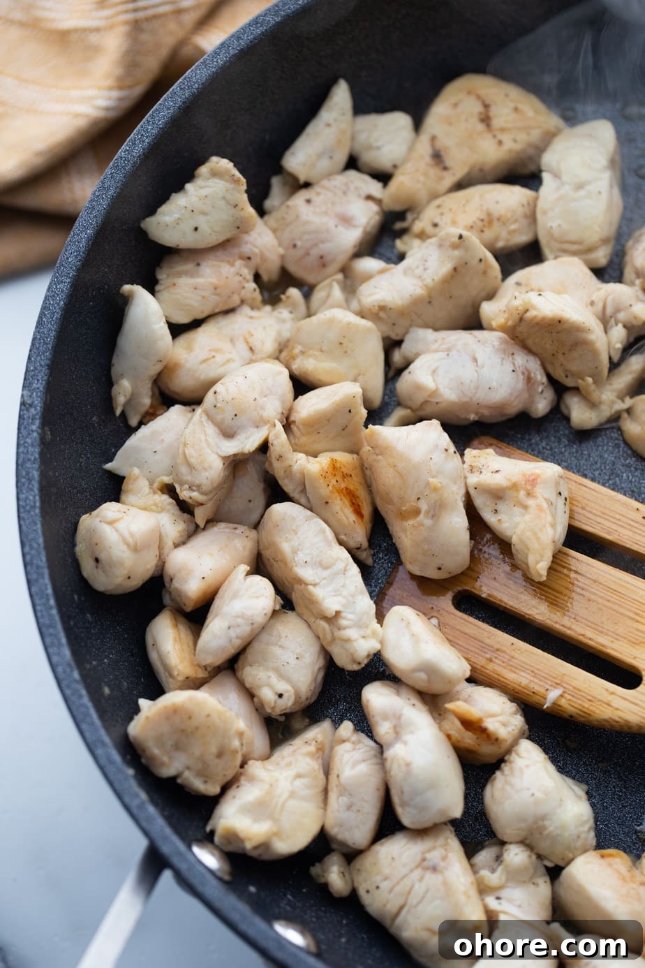 Hibachi Chicken Recipe: Tender Grilled Chicken with Garlic Butter 5 Diced chicken is being cooked in a large skillet.