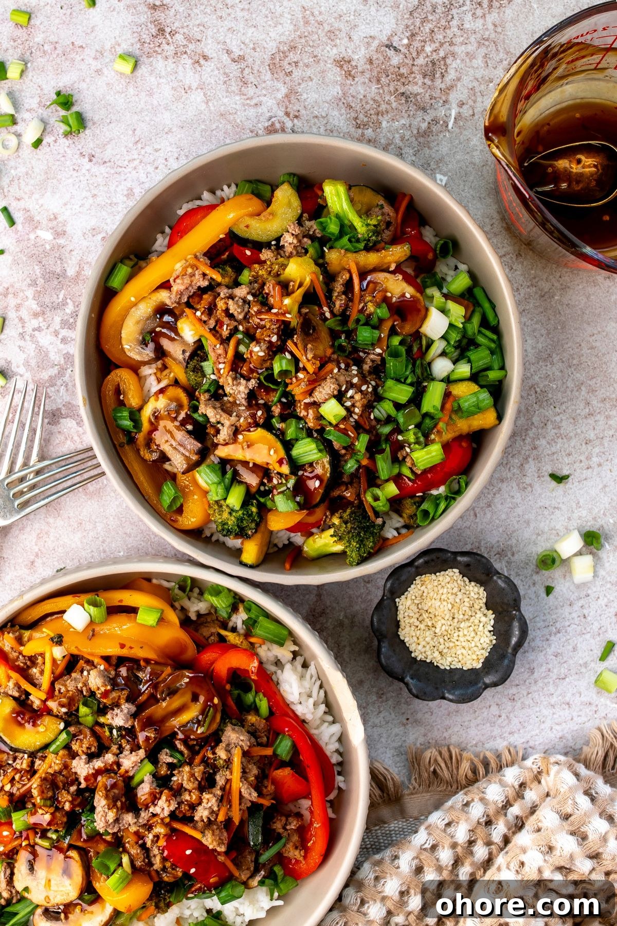 Quick Garlic Ground Beef Stir-Fry Recipe for Weeknight Dinners 2 White bowls with ground beef stir fry in it and onions on the side.