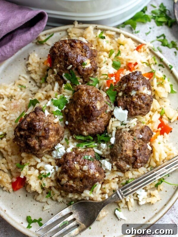 White plate with a silver fork and rice and meatballs.