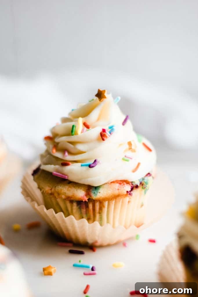 Close-up of a funfetti cupcake on a white surface.
