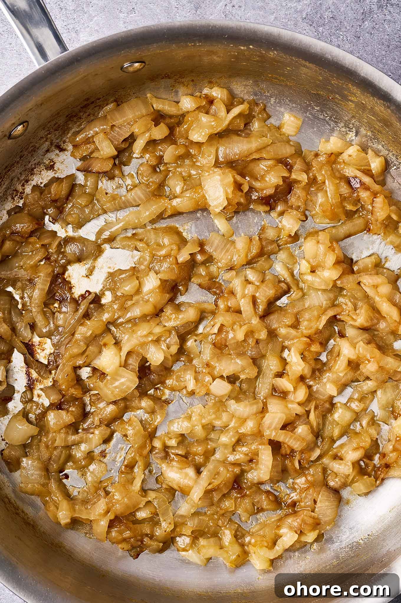 Perfect Caramelized Onions: Simple Step-by-Step Recipe 2 A stainless steel skillet filled with perfectly caramelized onions.