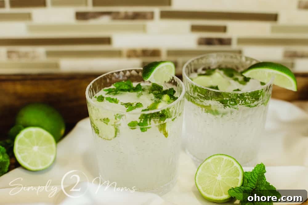 Photo of two Cuban mojitos on a tray with fresh limes and mint garnish