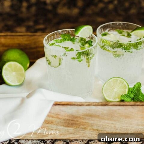 photo of two glasses of keto mojitos with fresh lime and mint garnish on a wood tray