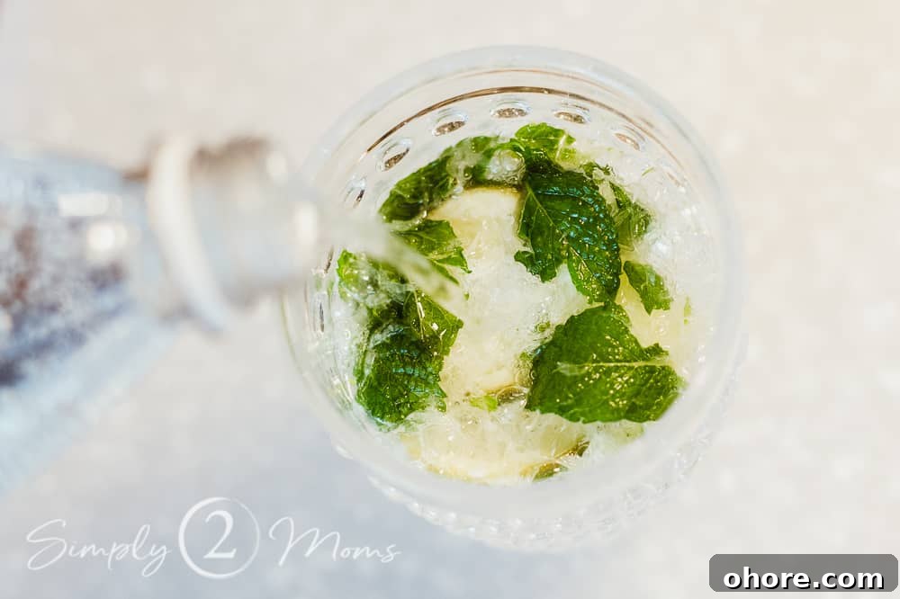 photo of seltzer being added to muddled mint and lime wedges