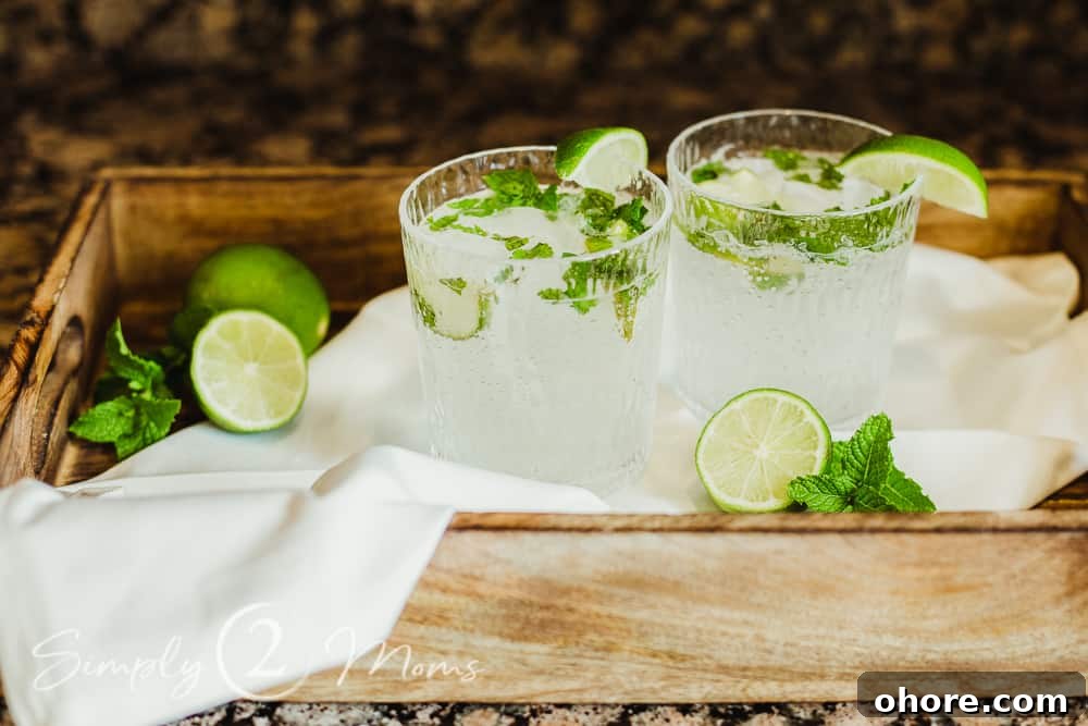 photo of two glasses of keto mojitos with fresh lime and mint garnish on a wood tray