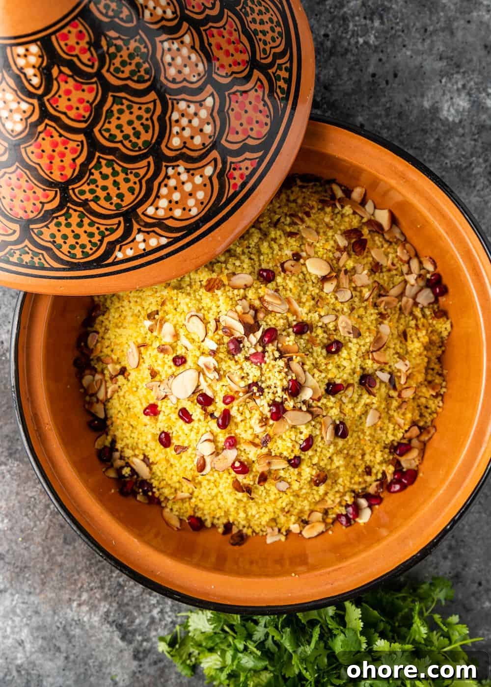 overhead: moroccan couscous with pomegranate arils and slivered almonds in a tagine