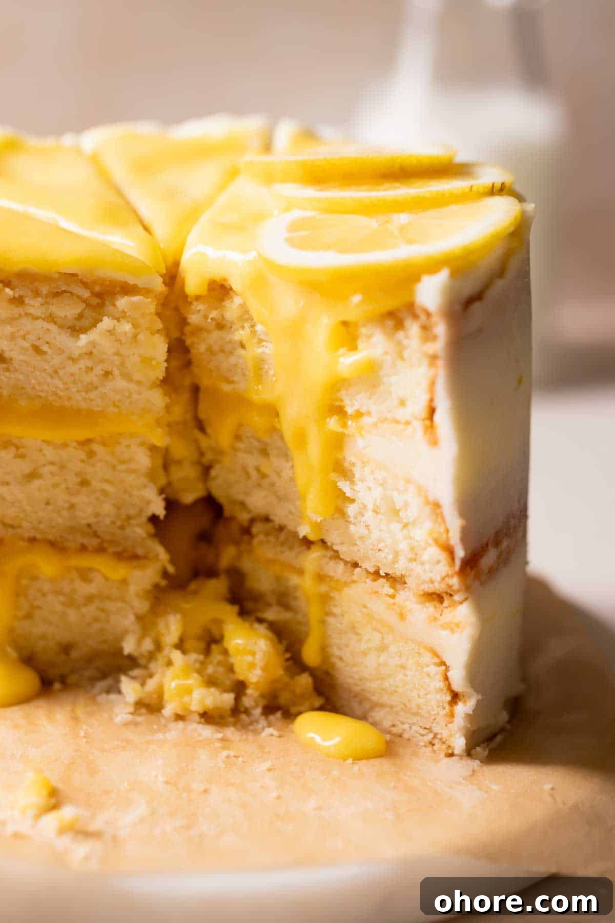 Zesty Lemon Bar Cake Recipe with Tender Shortbread Crust 2 lemon bar cake with lemon curd and fresh lemon slices on top.