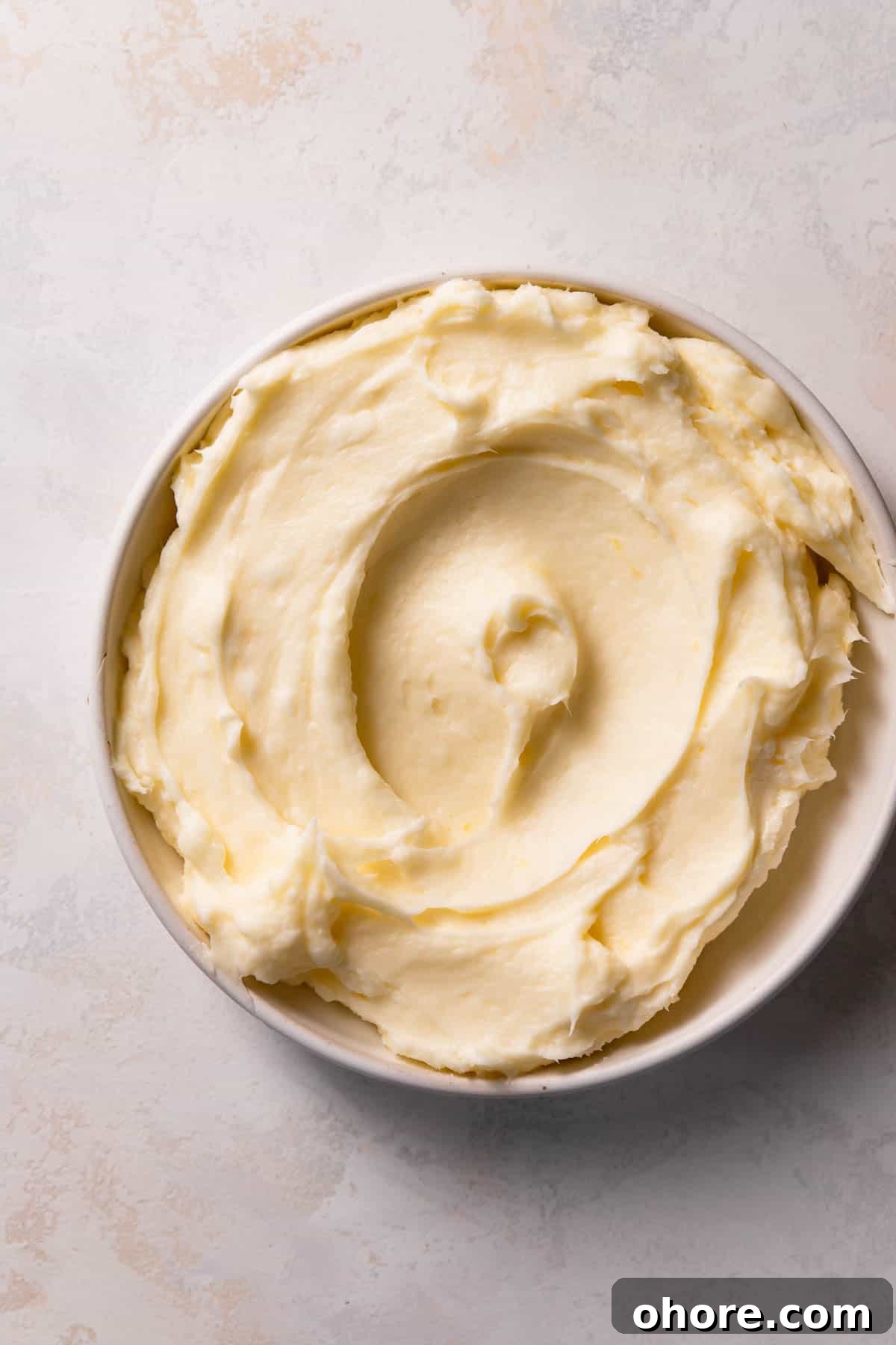 Zesty Lemon Bar Cake Recipe with Tender Shortbread Crust 11 lemon cream cheese frosting in a white bowl.