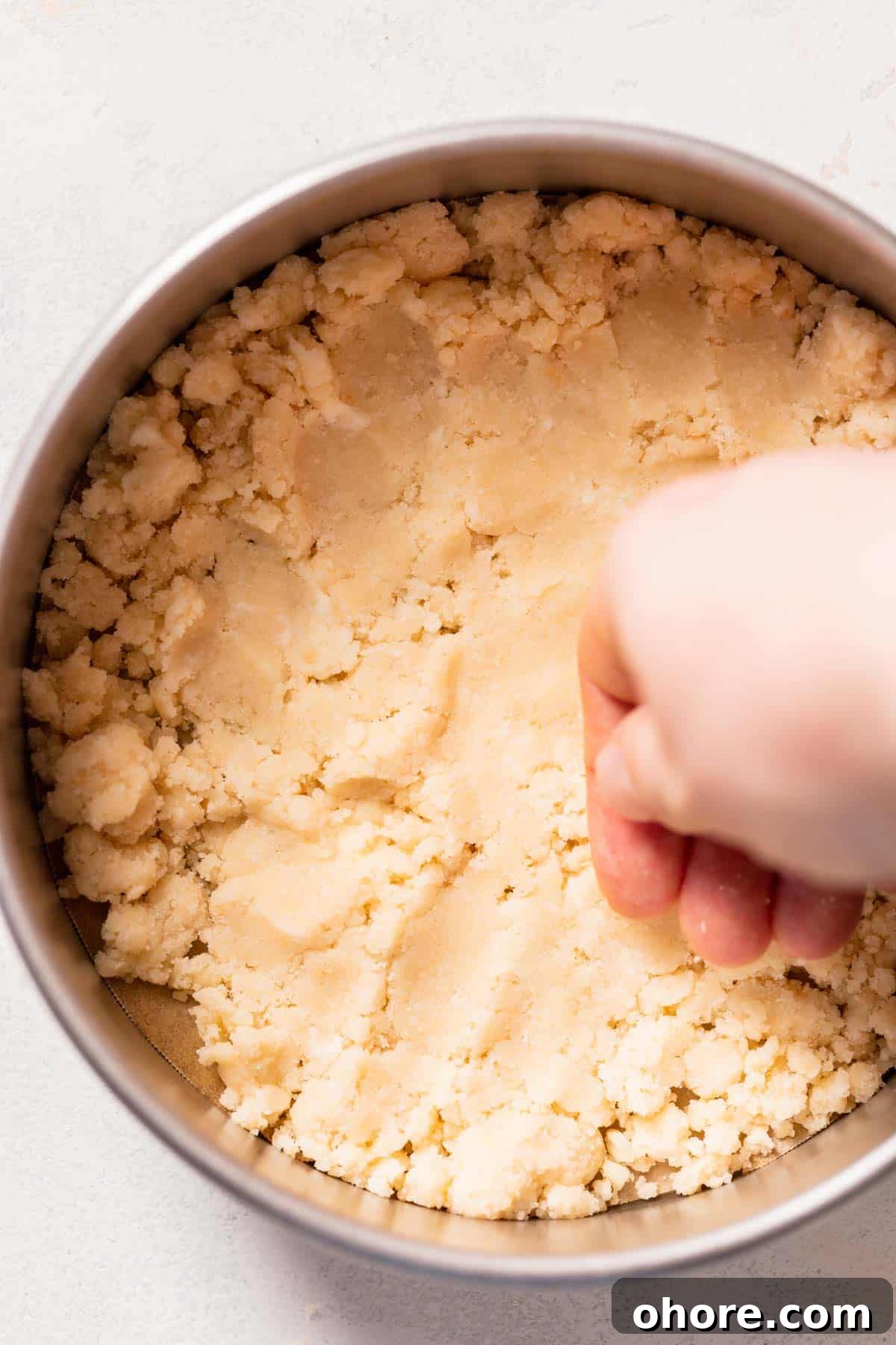Zesty Lemon Bar Cake Recipe with Tender Shortbread Crust 6 a hand pressing shortbread crust into a cake pan.