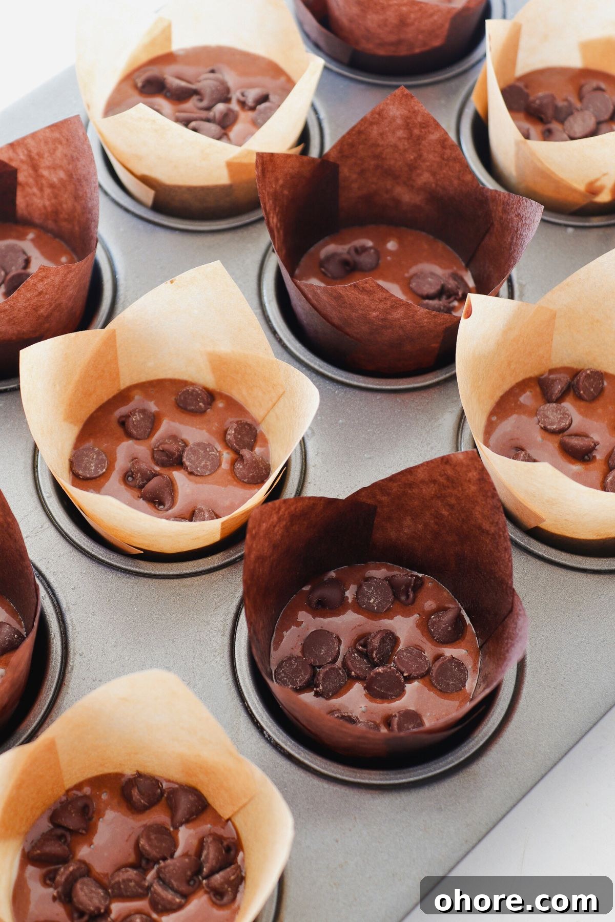 Decadent Double Chocolate Chip Muffins Recipe 6 Uncooked double chocolate chip batter in a paper liners in muffin tin.