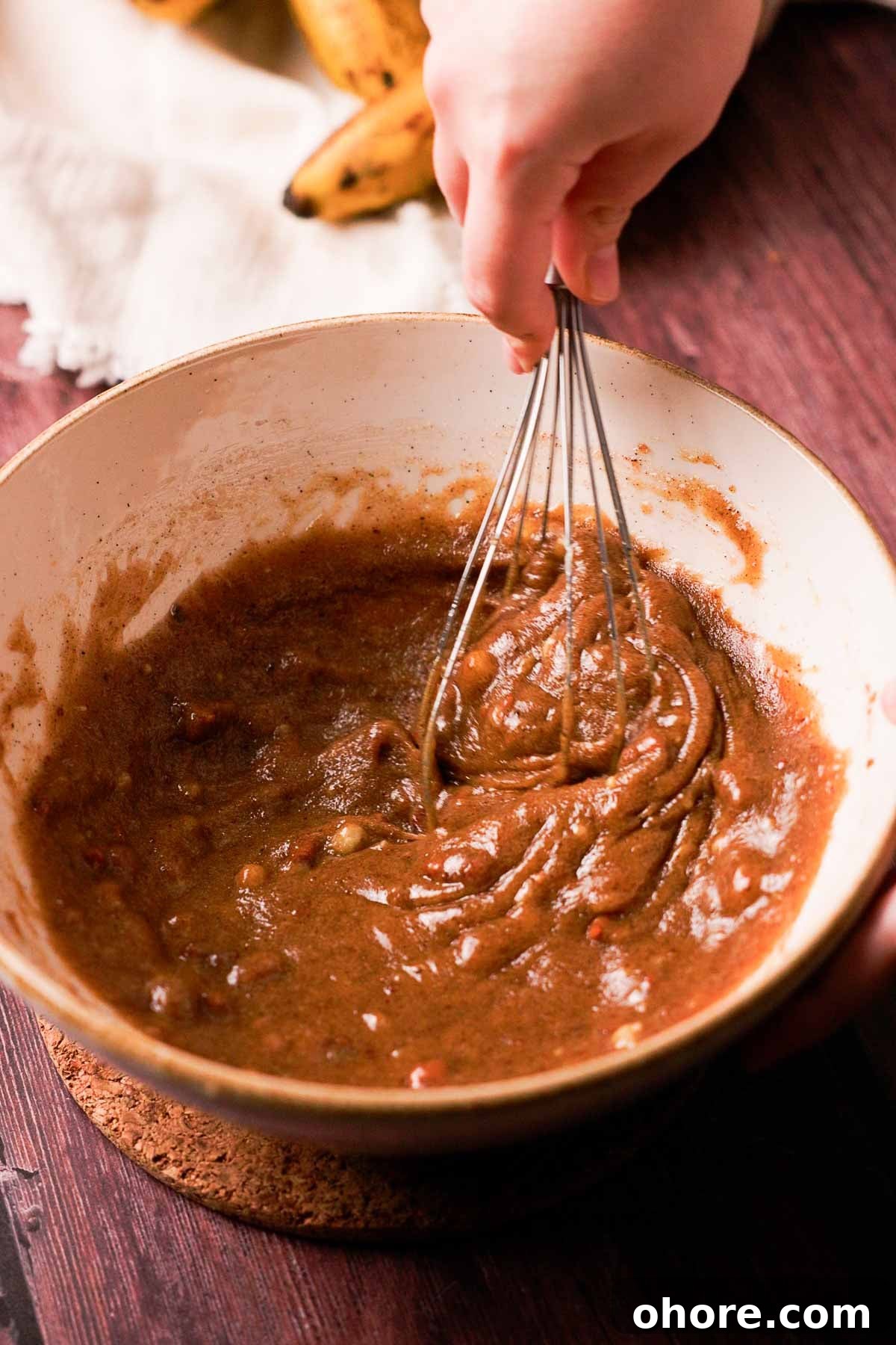 whisking banana bread cookie wet ingredients in a large bowl with a wire whisk