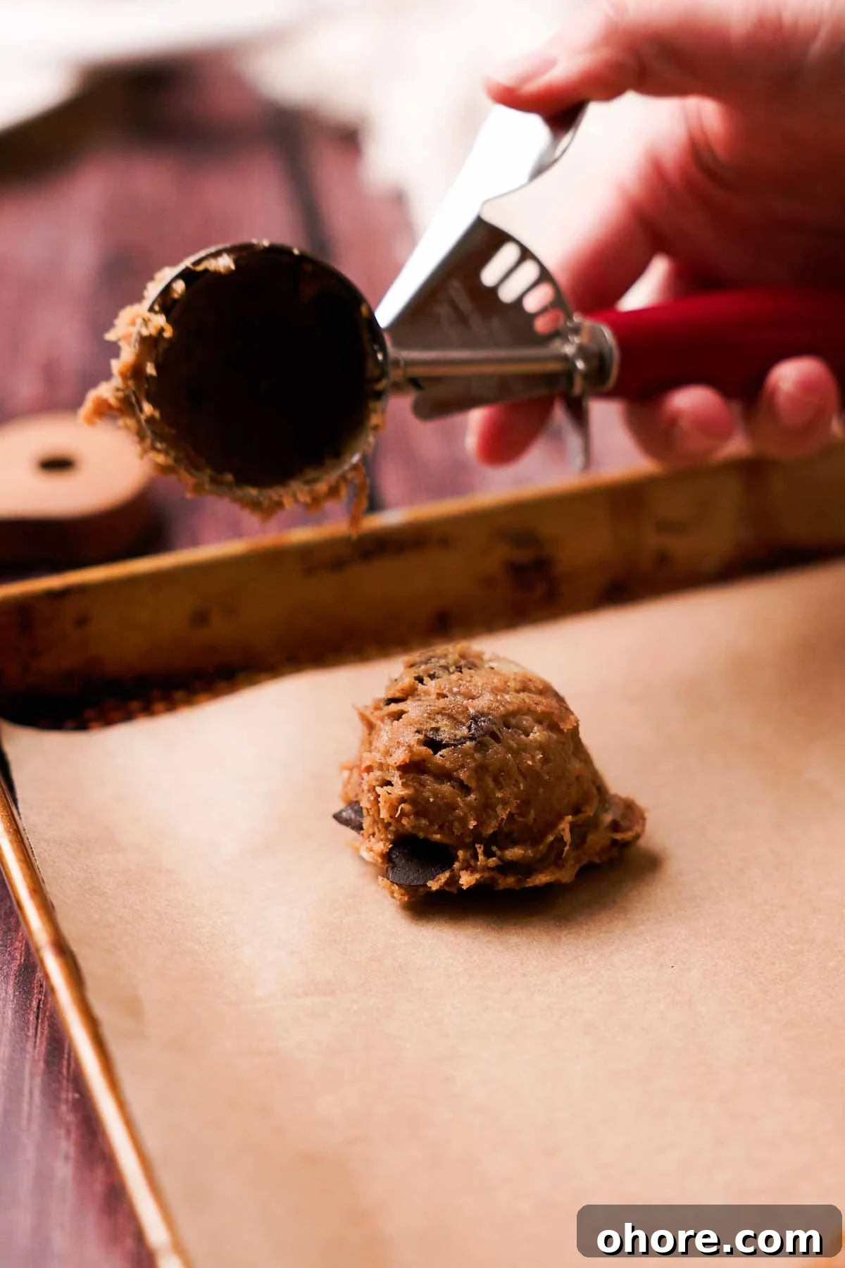 scooping banana bread cookie dough onto parchment paper sheet