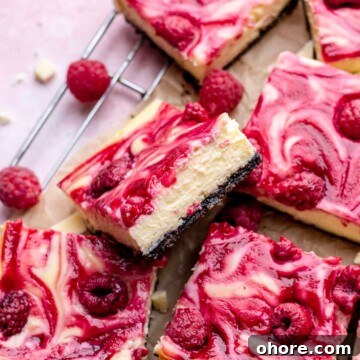 Slices of white chocolate raspberry cheesecake bars on a wire rack.