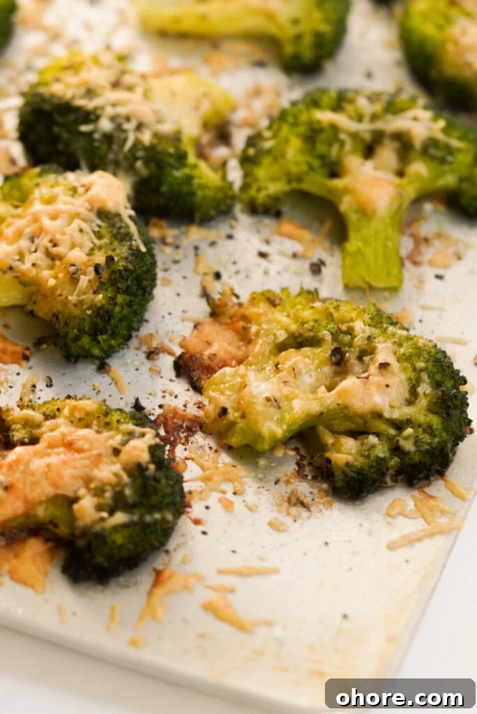 Crispy Smashed Broccoli with Parmesan and Garlic 11 closeup shot of baked parmesan smashed broccoli florets on a baking sheet.