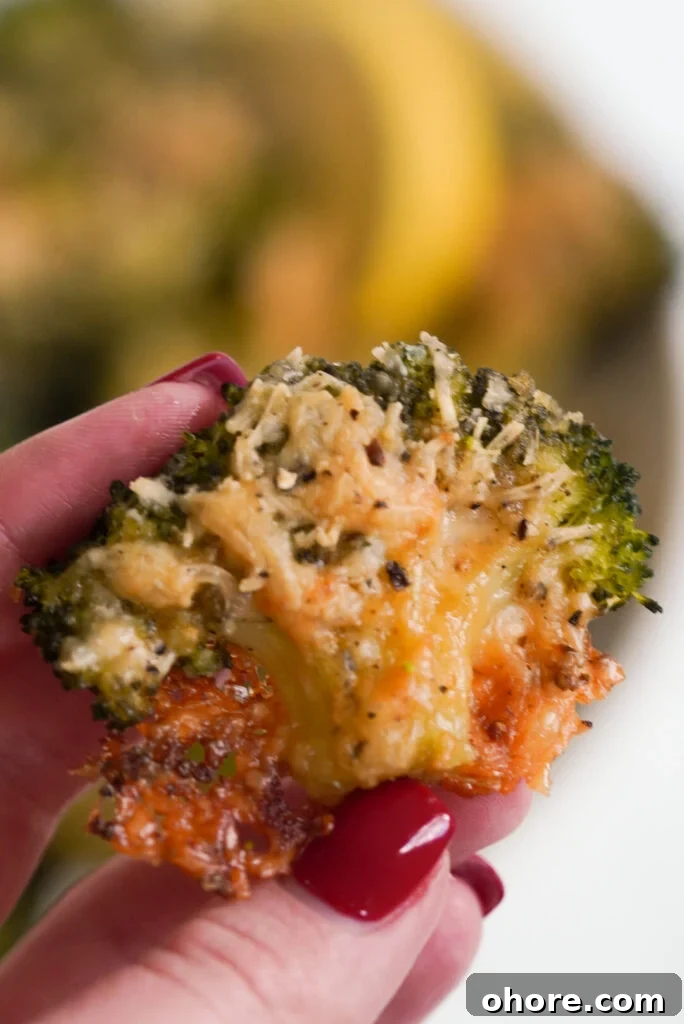 Crispy Smashed Broccoli with Parmesan and Garlic 13 hand holding a floret of crispy, cheesy smashed broccoli parmesan.